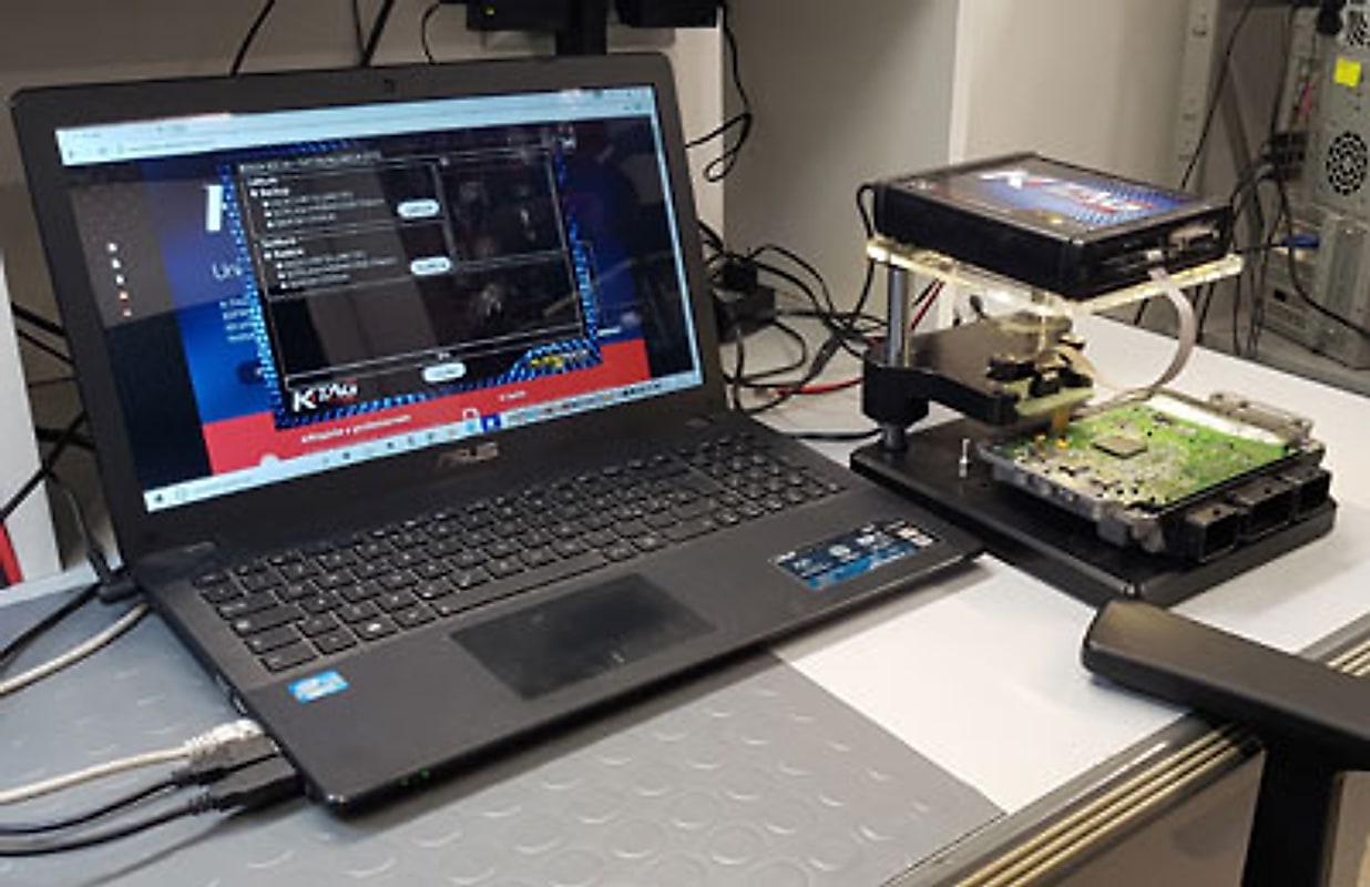 Una centralina elettronica aperta sul banco, collegata al computer di programmazione.