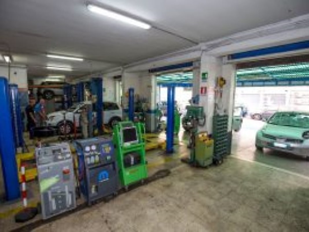 La corsia dell'officina con i banchi diagnostici e le vetture sui ponti.