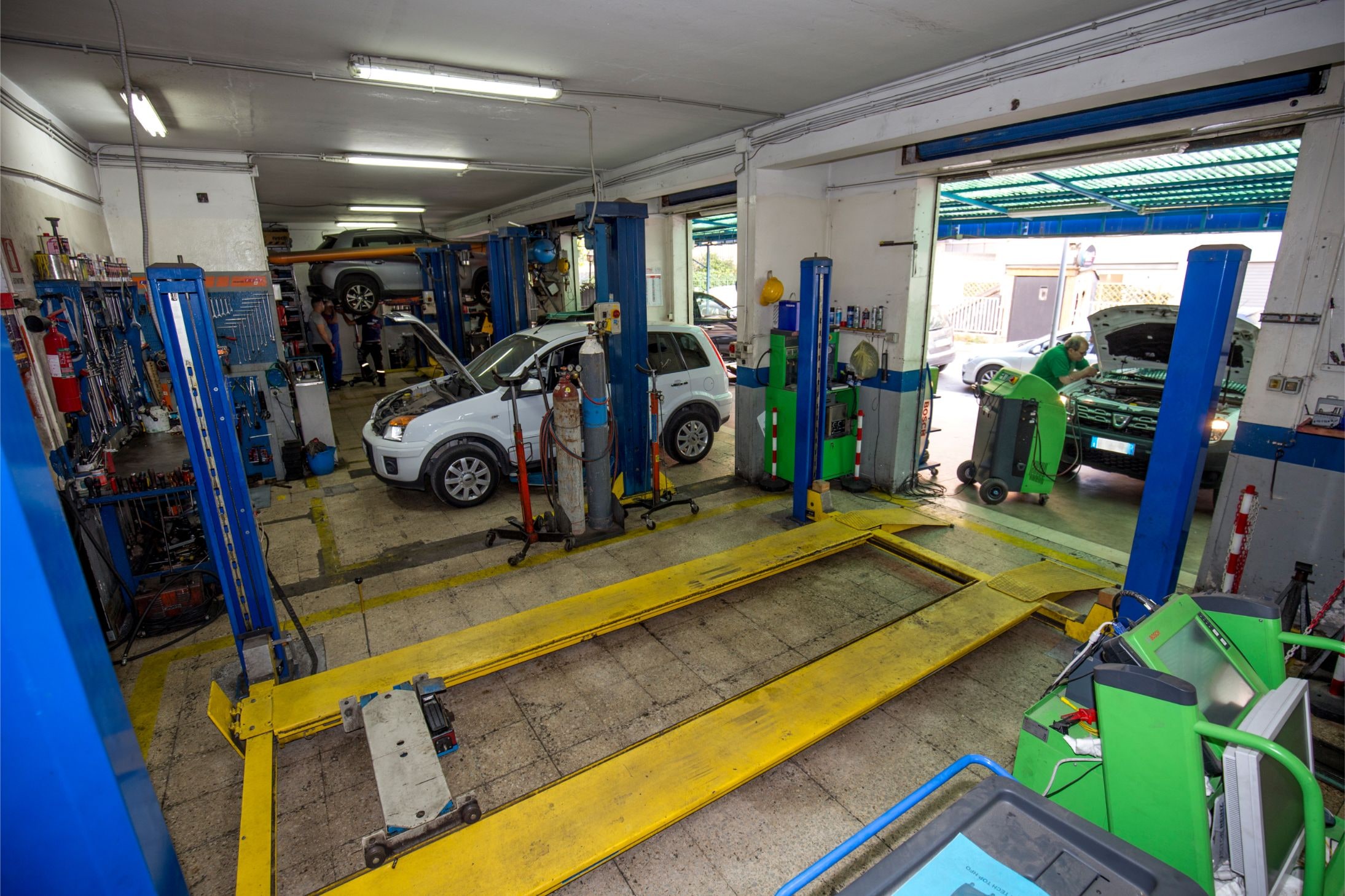 L'interno dell'officina: la corsia dei ponti a due colonne, la pedana di assetto e i banchi diagnostici.