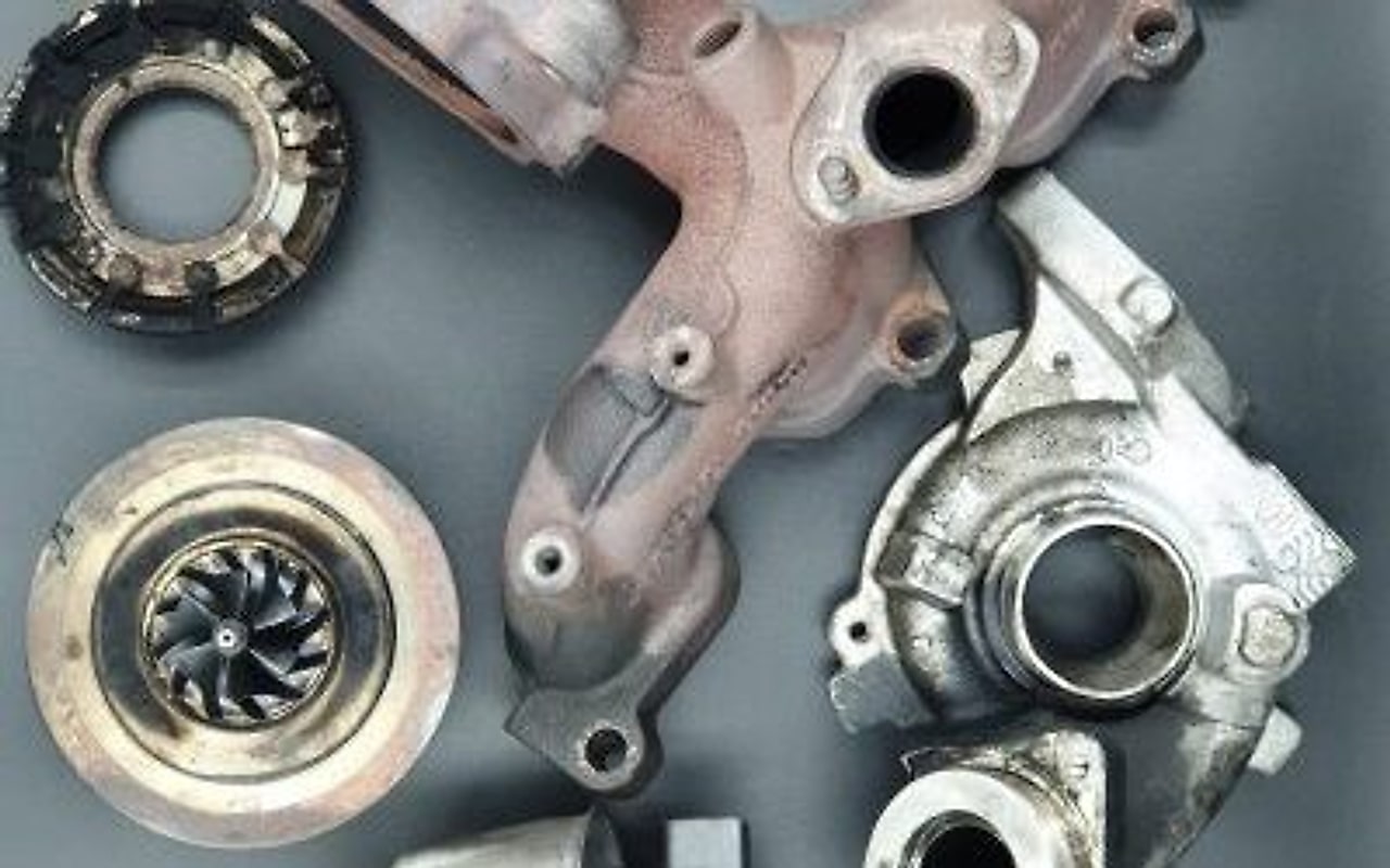 Un turbocompressore smontato sul banco: alloggiamento, girante del compressore e collettore.